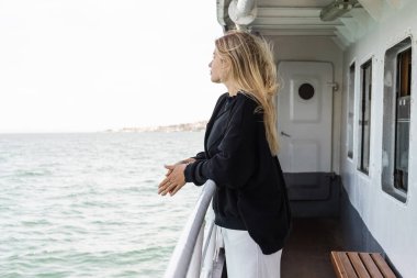 İstanbul Boğazı 'ndan geçen feribottan denize bakan siyah kazaklı genç bir kadın. 