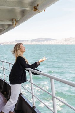 side view of woman in black sweater looking at sea from ferry boat crossing bosporus in istanbul  clipart