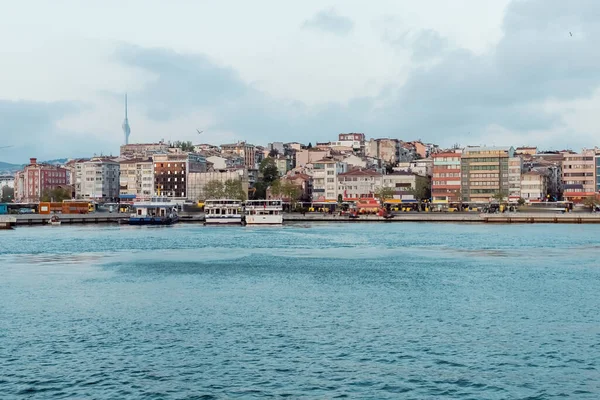 Diferentes barcos y barcos en el muelle cerca de edificios en Estambul - foto de stock