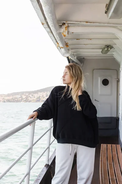 Femme blonde en pull noir regardant la mer de ferry bateau traversant le bosphore à Istanbul — Photo de stock