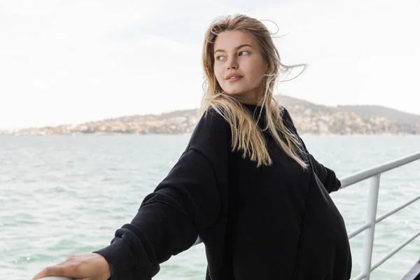 Hübsche Frau im schwarzen Pullover, die von einer Fähre über den Bosporus in Istanbul aufs Meer blickt — Stockfoto