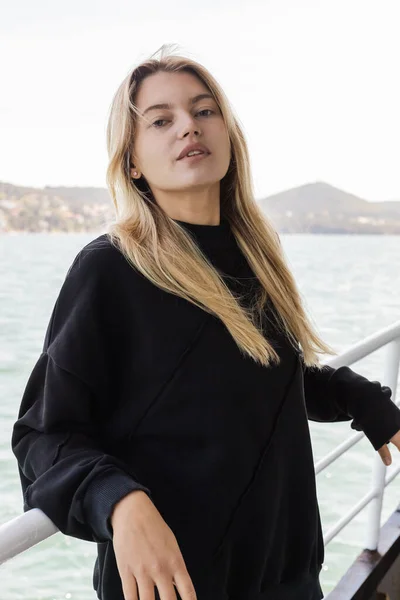 Young blonde woman in black sweater looking at camera from ferry boat crossing bosporus in istanbul — Stock Photo