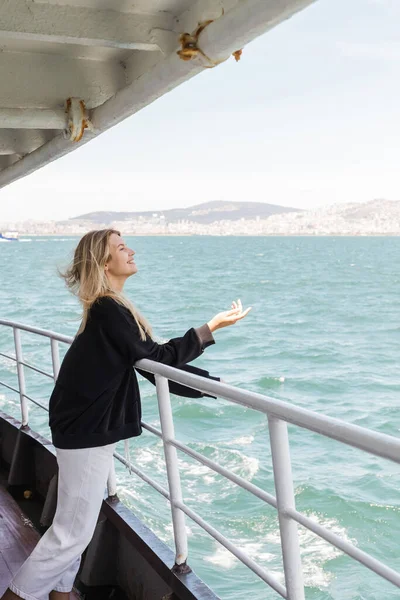 Seitenansicht einer Frau im schwarzen Pullover, die von einer Fähre über den Bosporus in Istanbul aufs Meer blickt — Stockfoto
