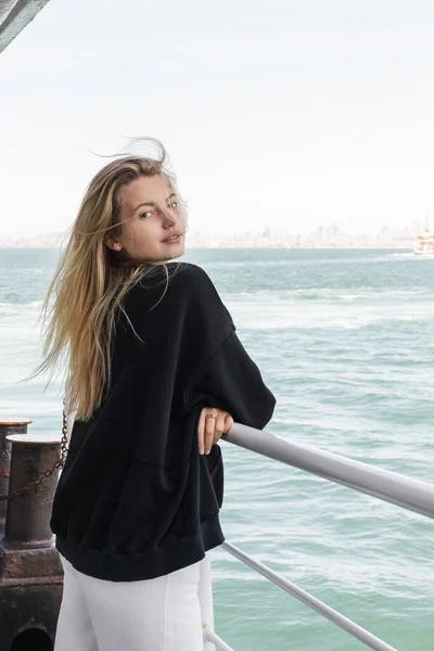 Blonde junge Frau im Pullover blickt von der Fähre über den Bosporus in Istanbul in die Kamera — Stockfoto