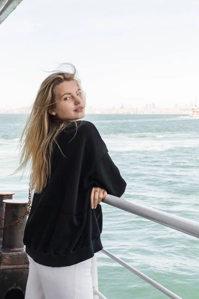 Blonde young woman in sweater looking at camera from ferry boat crossing bosporus in istanbul — Stock Photo