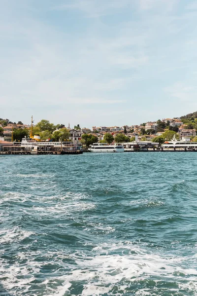 Modern boats on bosporus near pier and houses in seashore of istanbul — Stock Photo