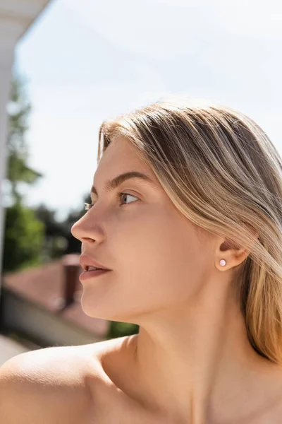 Portrait de jeune femme blonde à l'épaule nue regardant loin — Photo de stock