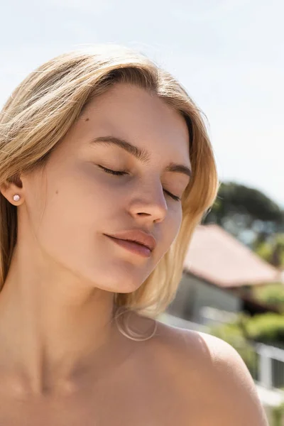Portrait of young blonde woman with bare shoulder and closed eyes in turkey — Stock Photo