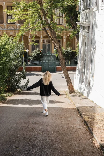 Vue arrière de la jeune femme blonde en tenue tendance marchant dans la rue en dinde — Photo de stock