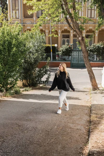 Happy blonde woman in trendy outfit walking on street in turkey — Stock Photo