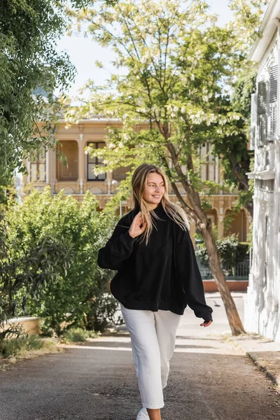 Fröhliche und blonde Frau im trendigen Outfit, die auf der Straße in der Türkei spaziert — Stockfoto