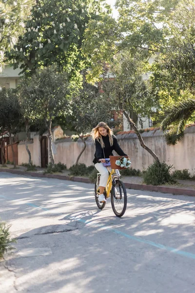 Молода блондинка в модному вбранні їзда на велосипеді на сонячній вулиці в Туреччині — стокове фото