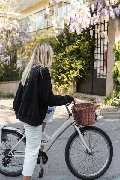 Вид ззаду блондинки в модному вбранні, що стоїть біля велосипеда на вулиці в Туреччині — стокове фото