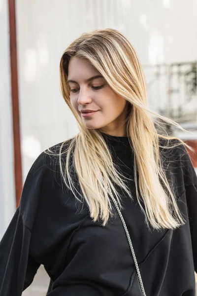 Portrait de jeune femme blonde en pull noir dans la rue en dinde — Photo de stock