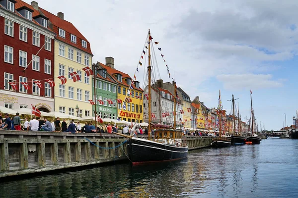 COPENHAGEN, NYHAVN - CIRCA HAVN Temmuz 2022: Kopenhag 'ın merkezindeki kanal ve cadde, Kongens Nytorv ve marina arasında yer almaktadır. Tarihi apartmanların, Danimarka bayraklarının, teknelerin ve turistlerin görünür renkli cepheleri.                            