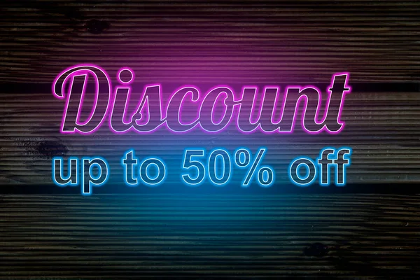İndirim% 50 'ye çıktı. Ahşap arka planda neon ışığı. Geceleri parlak reklamlar..