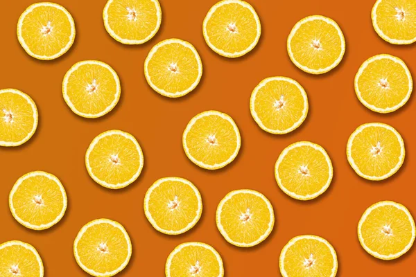 Slices of yellow oranges on an orange background.