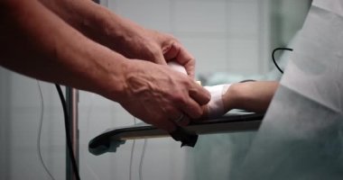 Hemşire damar içi infüzyon yapar ve ameliyata hazırlanır. Kateterli bir elin yakın çekimi..