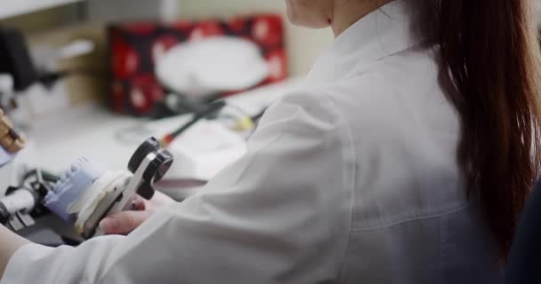 Zubní technik drží v rukou maketu čelistního artikulátoru.. — Stock video