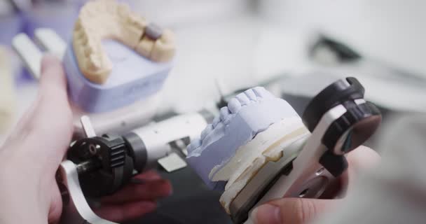 Egy fogtechnikus az állkapocs artikulátor mintáját tartja a kezében.. — Stock videók