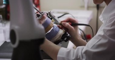 Bir diş teknisyeni elinde çene eklem makinesinin maketini tutuyor..