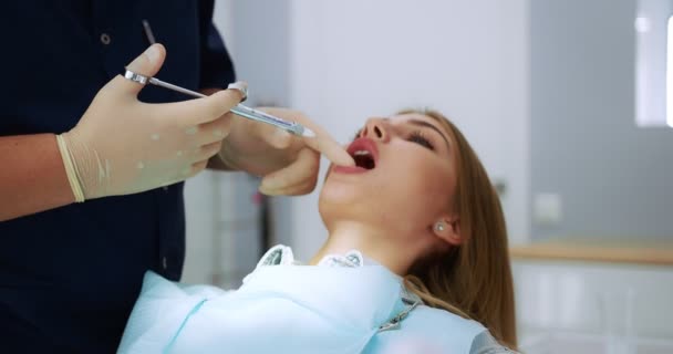 Dentista da una inyección analgésica en el diente de una mujer hermosa. — Vídeo de stock