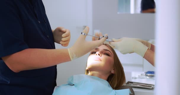 Tandarts geeft een pijnstillende injectie in de tand van een mooie vrouw. — Stockvideo