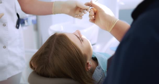 Dentista realiza um exame usando um espelho dental uma mulher — Vídeo de Stock