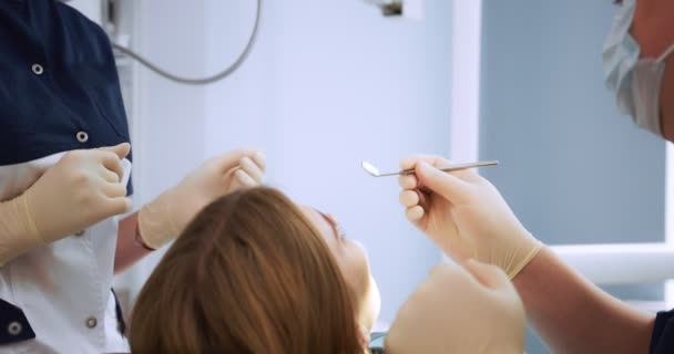 O dentista examina a cavidade oral das mulheres usando um espelho dentário. — Vídeo de Stock