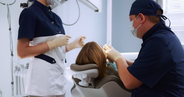 Dentista examina uma paciente do sexo feminino usando um espelho dental — Vídeo de Stock