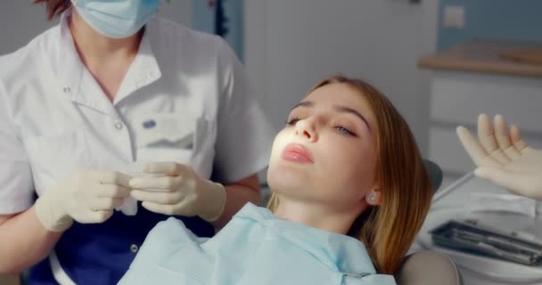 Dentysta stosuje zwijacz do pacjenta przed profesjonalnym czyszczeniem zębów — Wideo stockowe