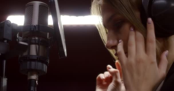 Όμορφη γυναίκα με ακουστικά ακούγοντας το τραγούδι της στο στούντιο ηχογράφησης — Αρχείο Βίντεο