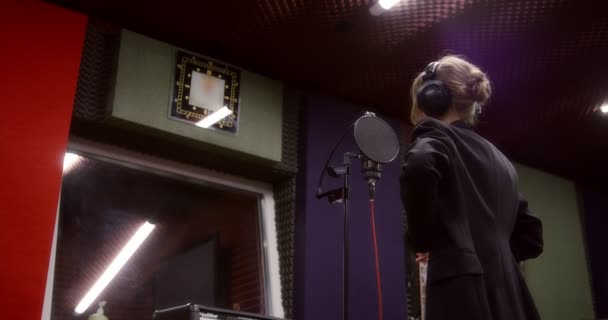 Donna in cuffia si prepara a registrare una canzone in uno studio di registrazione. — Video Stock