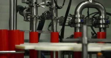 Makine yağı üretim tesisi. Kırmızı plastik şişeler kayganlaştırıcıyı doldurmak ve paketlemek için konveyör hattı boyunca hareket eder. Endüstriyel işletmeler için geliştirme, depolama ve makine yağı. Kırmızı kamerayla çekilmiş.