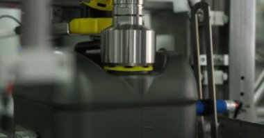 Gri plastik şişeler motor yağını doldurmak ve paketlemek için konveyör hattı boyunca hareket eder. 