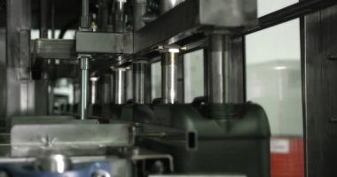 Gri plastik şişeler motor yağını doldurmak ve paketlemek için konveyör hattı boyunca hareket eder. 