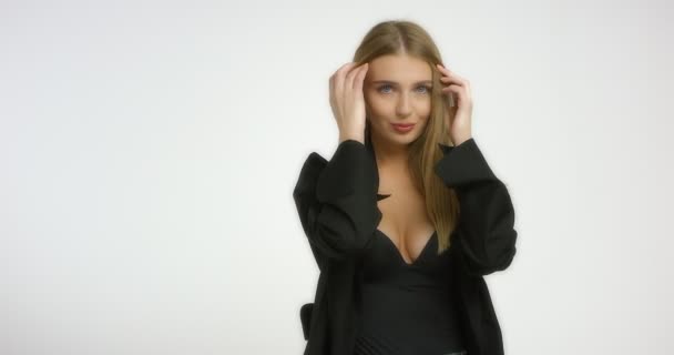 Schöne junge Frau posiert im Studio vor der Kamera auf weißem Hintergrund. — Stockvideo