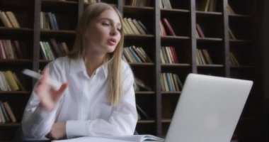 Beyaz gömlekli bir iş kadını dizüstü bilgisayarda çalışır ve notlar alır.. 