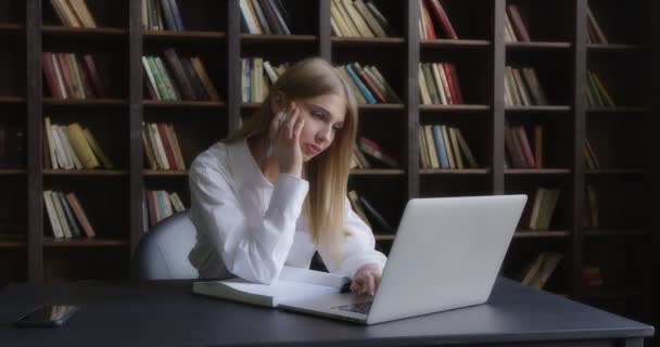 穿着白衬衫的女商人在笔记本电脑前工作并记笔记. — 图库视频影像
