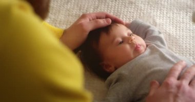 Mutlu genç baba, yeni doğmuş bebeği beşiğinde yatarken okşar..