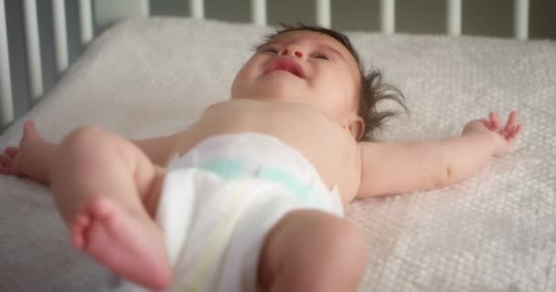 Neugeborenes in Windel liegt auf dem Rücken in leichtem Kinderbett. — Stockvideo