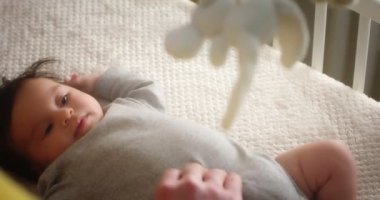 Mutlu genç baba, yeni doğmuş bebeği beşiğinde yatarken okşar..