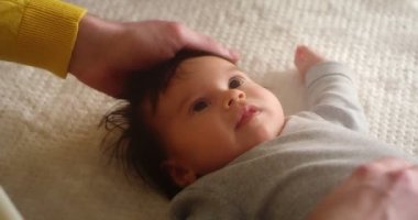 Mutlu genç baba, yeni doğmuş bebeği beşiğinde yatarken okşar..