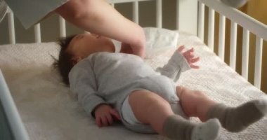 Sevgi dolu anne, yeni doğmuş bir bebeği bebek beşiğinde sırtüstü yatarak tarıyor.. 