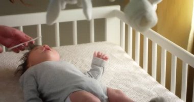 Sevgi dolu anne, yeni doğmuş bir bebeği bebek beşiğinde sırtüstü yatarak tarıyor.. 