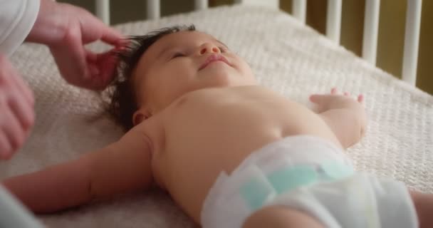 Fürsorgliche Mutter streichelt ein Neugeborenes in einer Windel, die auf dem Rücken im Kinderbett liegt. — Stockvideo