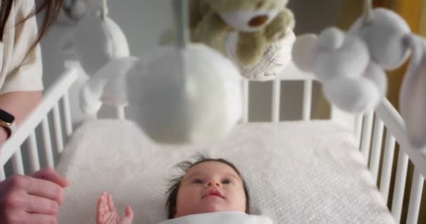 Nyfödd bebis i vit kroppskostym ligger på rygg i en lätt barnsäng. — Stockvideo