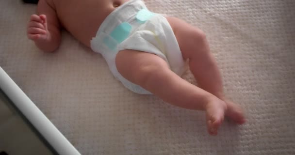 Newborn baby in a diaper lies on its back in a light child crib. — 图库视频影像