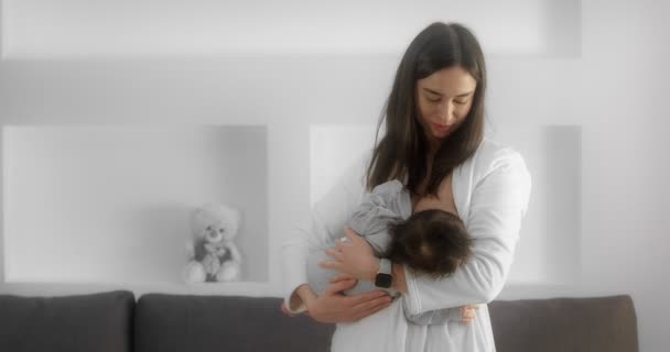 Mother is breastfeeding her newborn baby in the nursery. Mom cradles a infant. — стокове відео