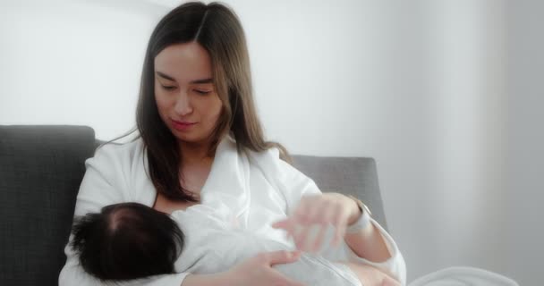 Mother is breastfeeding her newborn baby in the nursery. Mom cradles a infant. — Video